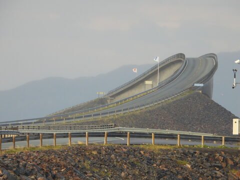 Pont sinueux sur la route de l'Atlantique en Norvège, entouré de montagnes et de rochers.