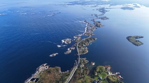 Route longeant la côte, bordée de maisons colorées, sur la route de l'Atlantique en Norvège.