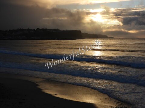Plage de Ballycastle en Irlande, avec des vagues et un ciel nuageux au crépuscule.
