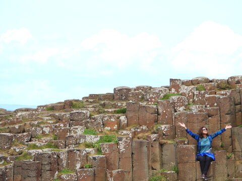 Chaussée des Géants en Irlande, avec des formations rocheuses hexagonales et une personne assise sur les pierres.