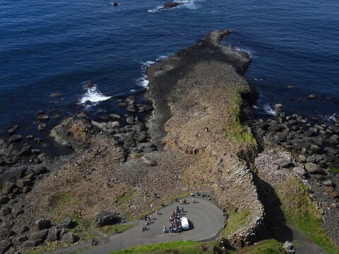 Chaussée de pierres hexagonales à la Chaussée des Géants, Irlande, avec des visiteurs et l'océan en arrière-plan.