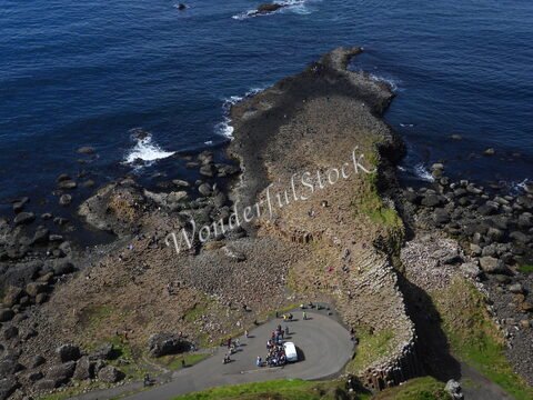 Chaussée de pierres hexagonales à la Chaussée des Géants, Irlande, avec des visiteurs et l'océan en arrière-plan.