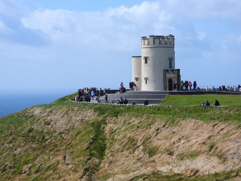 Un bâtiment blanc entouré de visiteurs sur les falaises de Moher, en Irlande.