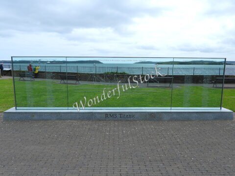 Mémorial en verre commémoratif du RMS Titanic à Cobh, Irlande, avec vue sur la mer et des bancs en arrière-plan.