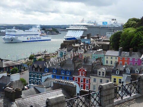 Maisons colorées à Cobh, en Irlande, avec des ferries et un paquebot dans le port.
