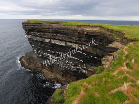 Falaises surplombant l'océan à Downpatrick Head, Irlande, avec des strates rocheuses noires et blanches.