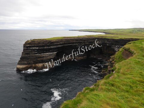 Falaises de Downpatrick Head en Irlande, surplombant l'océan, avec des vagues et une végétation verdoyante.
