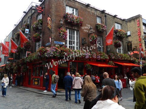 Temple Bar à Dublin, Irlande, avec des fleurs colorées et des passants devant le pub.