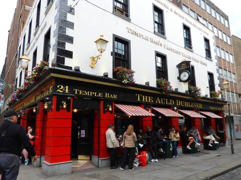 Pub The Auld Dubliner à Temple Bar, Dublin, Irlande, avec des fleurs aux fenêtres et des personnes assises à l'extérieur.