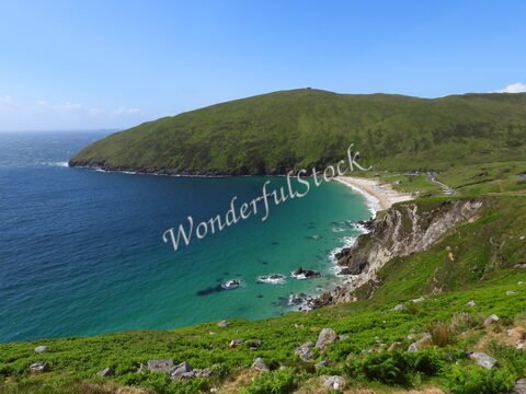 Plage et côtes verdoyantes à Keel, Irlande, avec des eaux turquoise et des rochers en bord de mer.