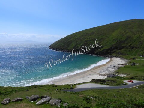 Plage de Keel en Irlande, avec une colline verte en arrière-plan et des vagues sur l'eau.