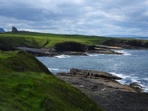 Falaises et côtes de Mullaghmore Head en Irlande, avec un château surplombant la mer et des prairies verdoyantes en arrière-plan.