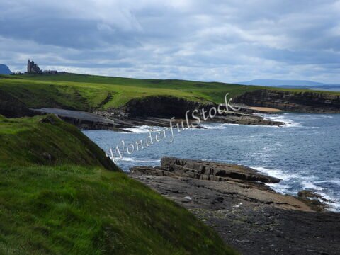 Falaises et côtes de Mullaghmore Head en Irlande, avec un château surplombant la mer et des prairies verdoyantes en arrière-plan.