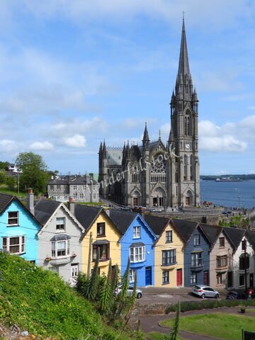 L'église Saint-Colman et des maisons colorées à Cobh, Irlande, avec un ciel partiellement nuageux.