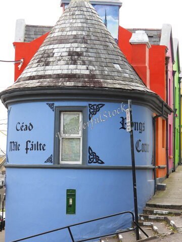 Un bâtiment coloré avec un toit conique et des inscriptions en irlandais à Cobh, Irlande.