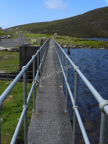 Passerelle en béton avec rampes, entourée de verdure, à Keel, Irlande.