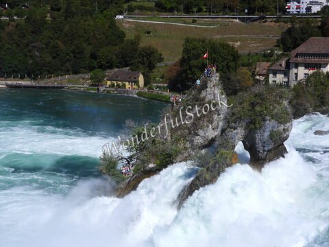 Chutes du Rhin en Suisse, avec des visiteurs sur les rochers et des eaux tumultueuses en arrière-plan.