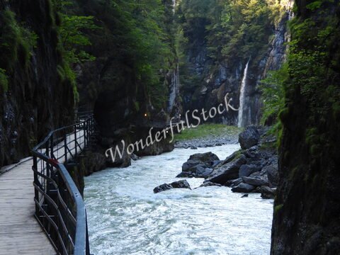 Gorges de l'Aar en Suisse, avec un sentier en bois et une cascade visible au fond, entourées de rochers et de végétation.