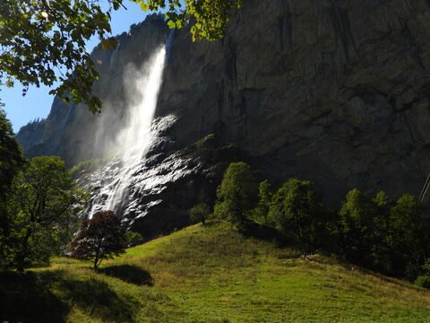Chute d'eau à Lauterbrunnen, Suisse, entourée d'arbres et de collines verdoyantes.
