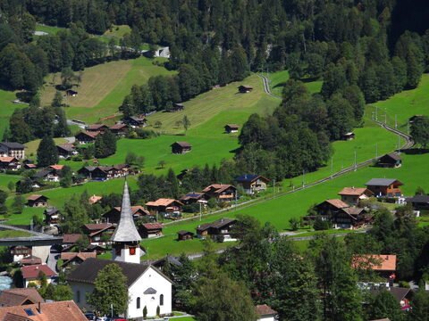 Lauterbrunnen en Suisse, avec des maisons traditionnelles et une église à flèche, entouré de collines verdoyantes.