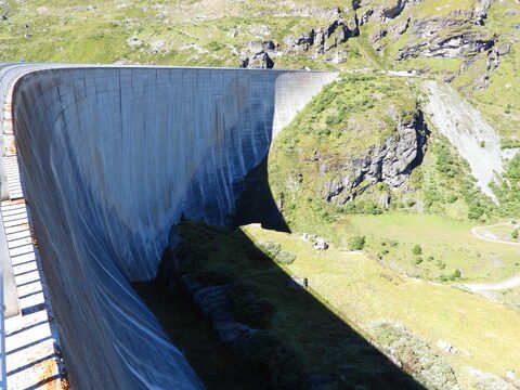 Barrage surplombant une vallée verdoyante à Moiry, en Suisse, avec des montagnes en arrière-plan et un ciel dégagé.