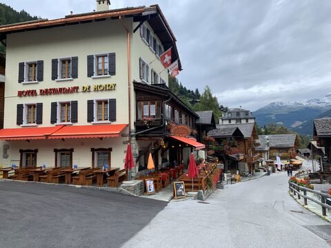 Hôtel Restaurant de Moiry à Grimentz, Suisse, avec des terrasses en bois et des montagnes en arrière-plan.