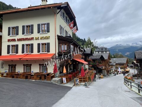 Hôtel Restaurant de Moiry à Grimentz, Suisse, avec des terrasses en bois et des montagnes en arrière-plan.
