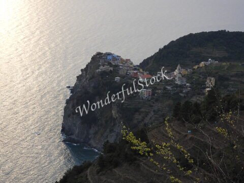 Village surplombant la mer à Monterosso, Italie, avec des maisons colorées et des collines verdoyantes en arrière-plan.