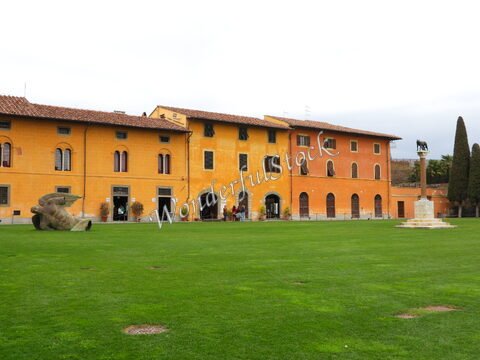Bâtiment historique avec des fenêtres à volets, sculpture sur la pelouse, à Pise, Italie.