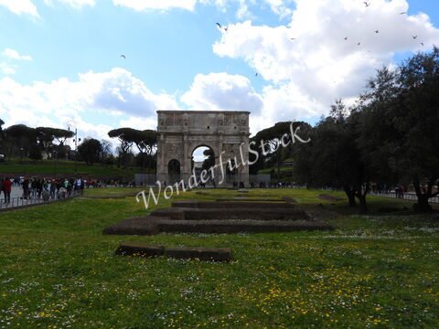 Arc de triomphe à Rome, Italie, avec des visiteurs et des arbres en arrière-plan sous un ciel nuageux.