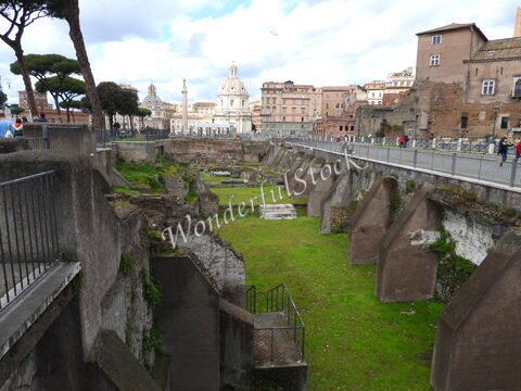 Ruines avec une verdure au centre, entourées de bâtiments historiques à Rome, Italie.