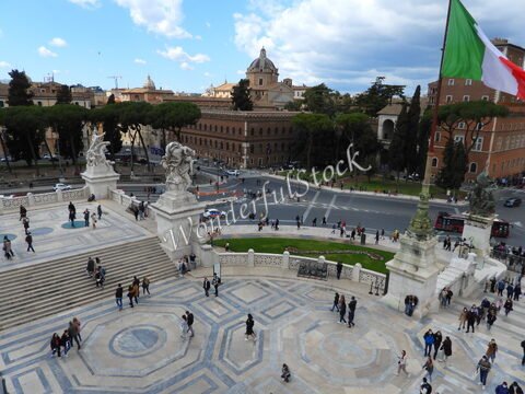 Place animée avec des visiteurs et des statues, à Rome, Italie, entourée de bâtiments historiques et d'arbres.