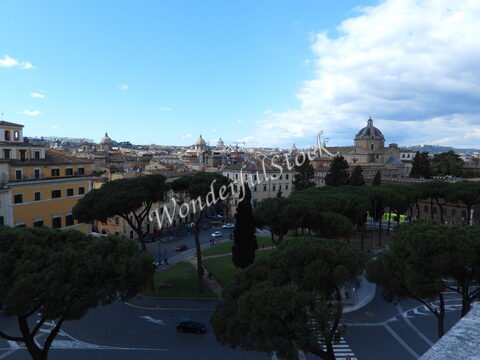 Vue sur des bâtiments et des arbres à Rome, Italie, avec un ciel partiellement nuageux.