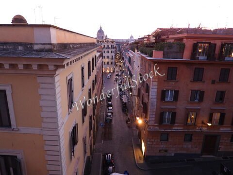 Ruelle animée à Rome, Italie, avec des bâtiments aux façades colorées et des lampadaires éclairant le chemin.