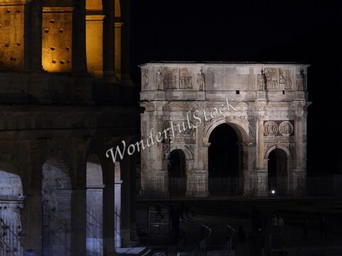 Arc de triomphe éclairé, près du Colisée, à Rome, Italie, avec des détails sculptés visibles dans la nuit.