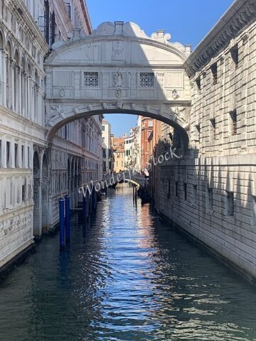 Pont en marbre sur un canal à Venise, Italie, avec des bâtiments historiques et des reflets dans l'eau.