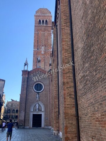 Édifice en briques avec un campanile à Venise, Italie, entouré de bâtiments anciens et d'une rue pavée.