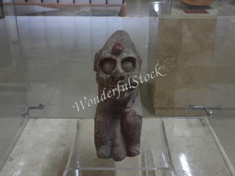 Sculpture précolombienne exposée à Calakmul, Mexique, représentant une figure humaine avec des détails stylisés et un socle en verre.