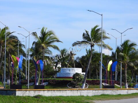 Statue au centre d'un rond-point, entourée de palmiers et de sculptures colorées, à Carmen, Mexique.