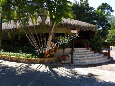 Bâtiment avec toit de chaume et plantes tropicales, situé à Ik Kil, Mexique.