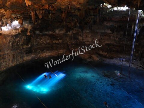 Cenote Samula au Mexique, avec des stalactites et des rayons de lumière illuminant l'eau turquoise.