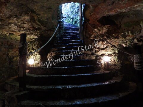 Escaliers en pierre menant à l'extérieur d'un cenote, Mexique. Éclairages et parois rocheuses visibles.