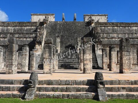 Ruines d'une pyramide avec des colonnes à Chichén Itzá, Mexique, sous un ciel bleu.