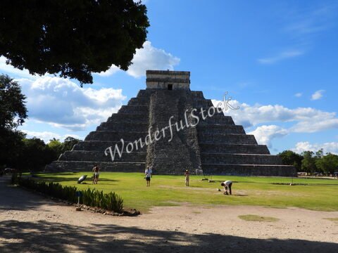 Pyramide à Chichen Itza, Mexique, entourée de visiteurs et d'arbres, sous un ciel partiellement nuageux.