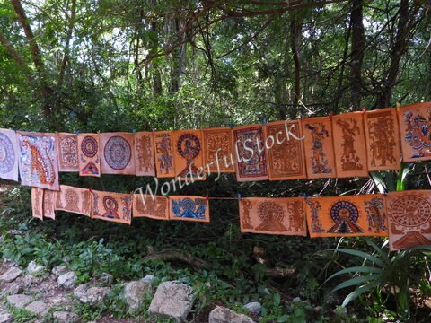 Des œuvres artisanales colorées suspendues entre les arbres à Itza, Mexique, présentant des motifs traditionnels.