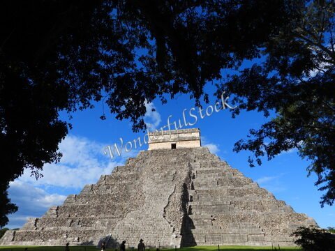Pyramide d'Itza, Mexique, entourée d'arbres et sous un ciel bleu, avec des marches visibles sur la structure.
