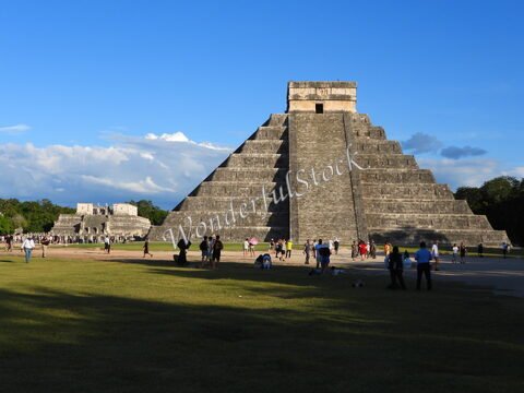Pyramide d'Itza au Mexique, entourée de visiteurs, avec un ciel bleu et des nuages en arrière-plan.