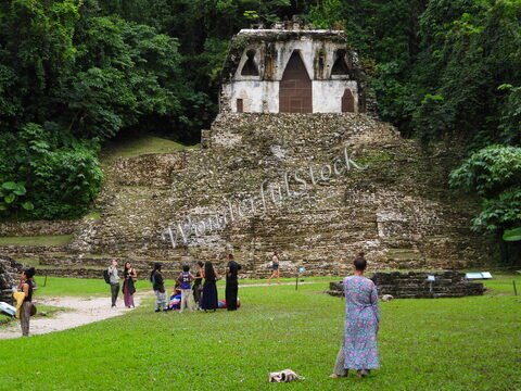Temple ancien à Palenque, Mexique, entouré de végétation luxuriante et de visiteurs explorant le site archéologique.