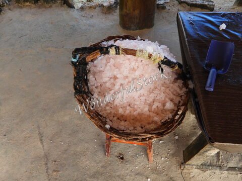 Sel de mer dans un panier en osier à Xtampu, Mexique, avec une pelle en plastique à côté sur une surface en bois.