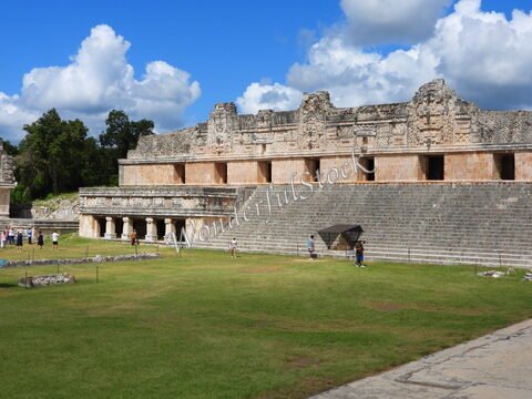 Ruines mayas d'Uxmal au Mexique, avec des gradins et des visiteurs, sous un ciel nuageux.